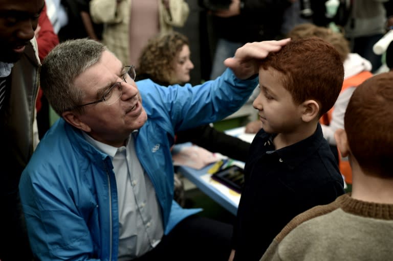 International Olympic Committee (IOC) chairman Thomas Bach speaks with a child during a visit to the Elaionas refugee camp in Athens, on January 28, 2016