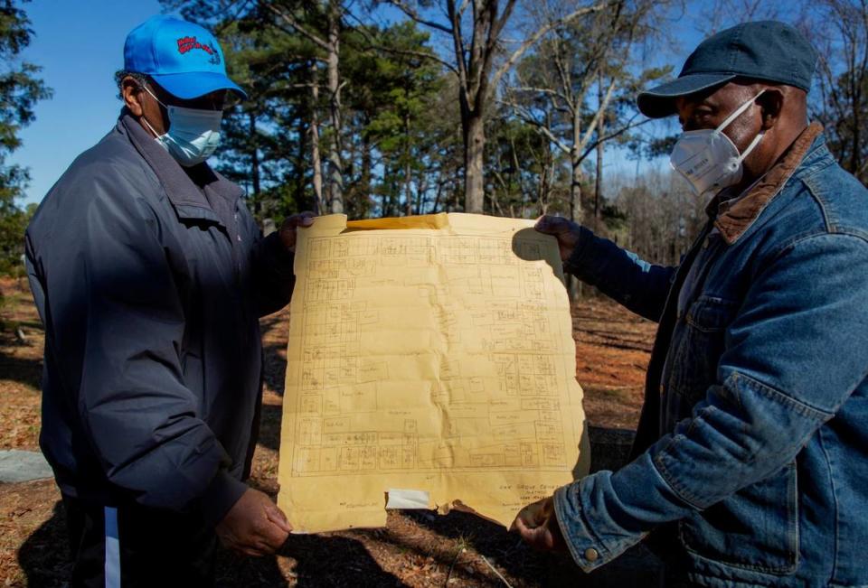 John Goode, left, and Albert Crenshaw hold up a 1938 map of the Oak Grove Cemetery, which was founded by freed African-Americans after the Civil War and now has lost more of its tree buffer to widening of the I-440 Beltline, that separated it from the rest of the Method community in the 1960s, on Wednesday, Feb. 17, 2021, in Raleigh, N.C.