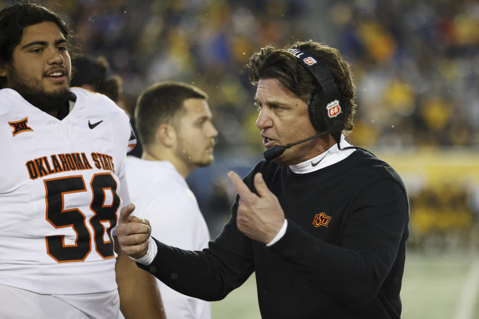 Oklahoma State head coach Mike Gundy, right, encourages his players after taking the lead during the second half of an NCAA college football game against West Virginia, Saturday, Oct. 21, 2023, in Morgantown, W.Va. Oklahoma State won 48-34. (AP Photo/Chris Jackson)