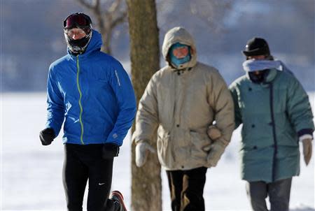 A jogger sprints ahead of a couple walking into the wind at Lake Harriet in Minneapolis, January 8, 2014. REUTERS/Eric Miller