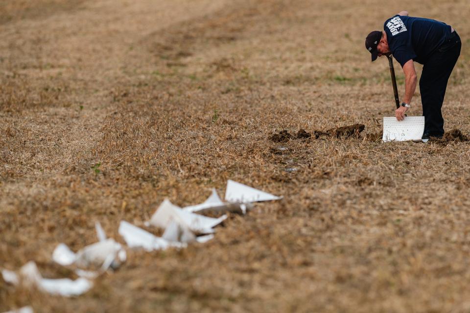 A Bolivar Fire Department firefighter works to contain residual oil runoff after a combine fire was extinguished in a soybean field in Lawrence Township.