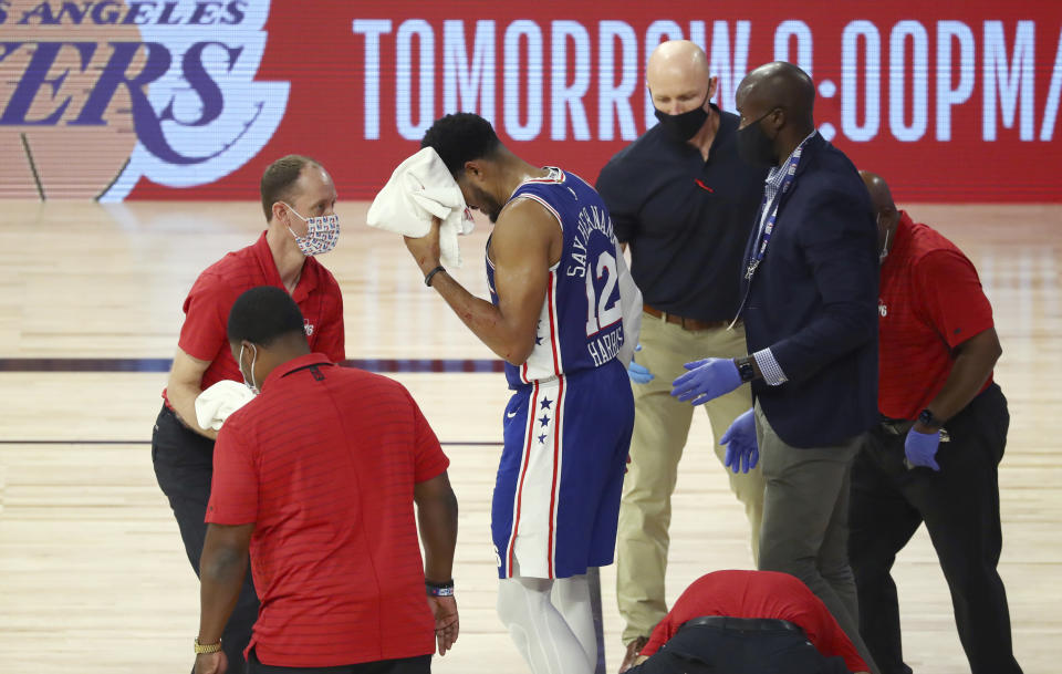 Philadelphia 76ers forward Tobias Harris (12) is attended to after hitting his head against the Boston Celtics during the third quarter of Game 4 of an NBA basketball first-round playoff series, Sunday, Aug. 23, 2020, in Lake Buena Vista, Fla. (Kim Klement/Pool Photo via AP)