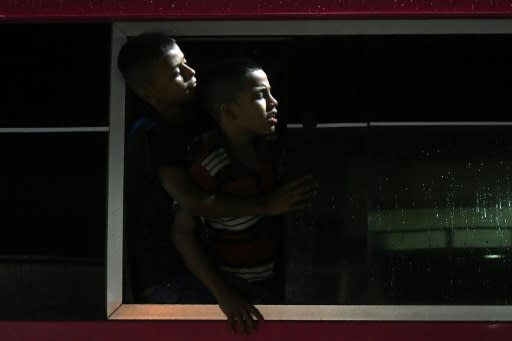 Two Honduran boys look out the window of a bus leaving San Pedro Sula at the start of a long and dangerous trip they hope will land them in the US