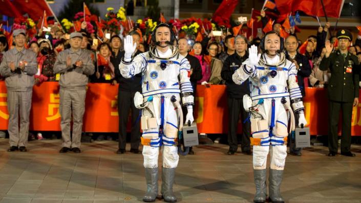 Chinese astronauts Jing Haipeng (R), Chen Dong wave before the launch of Shenzhou-11 manned spacecraft, in Jiuquan, China, October 17, 2016.