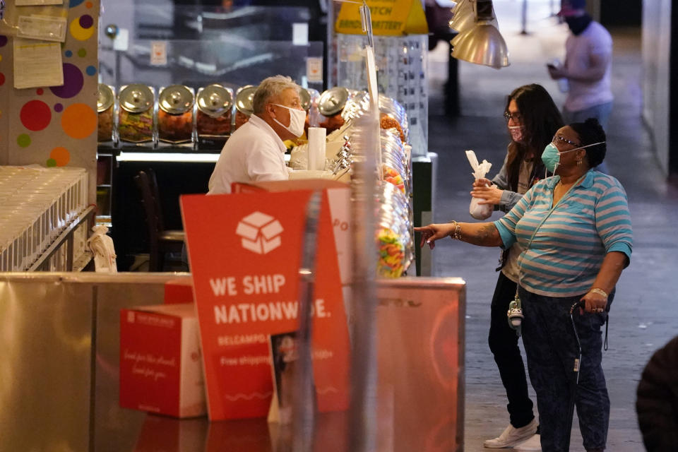 Customers buy goods at the Grand Central Market Monday, Nov. 16, 2020, in Los Angeles. California Gov. Gavin Newsom announced Monday, Nov. 16, 2020, that due to the rise of COVID-19 cases, Some counties have been moved to the state's most restrictive set of rules. The new rules begin, Tuesday, Nov. 17. (AP Photo/Marcio Jose Sanchez)