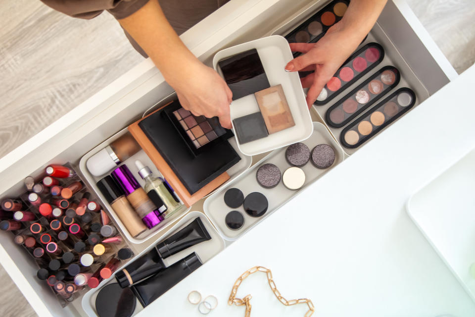 a person pulling makeup from a drawer