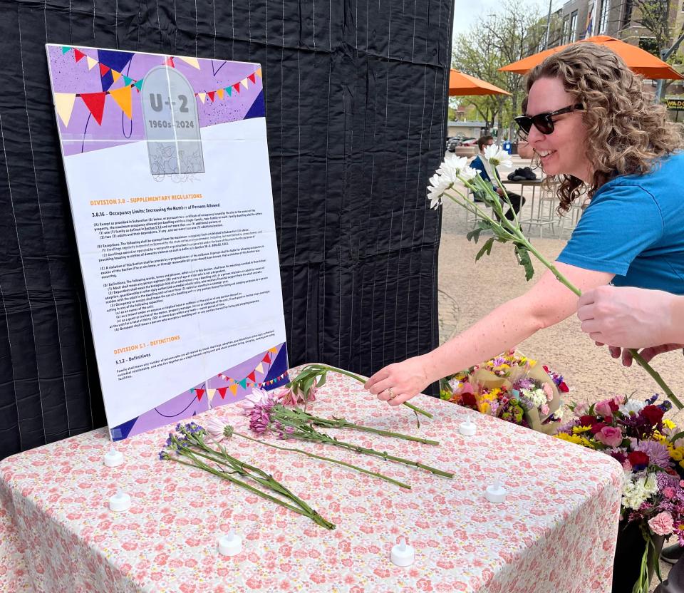 Kate Conley, co-lead of housing advocacy group YIMBY Fort Collins, places a flower on a table in front of the words of the U+2 ordinance at a rally on Sunday, May 5, 2024, in Oak Street Plaza.