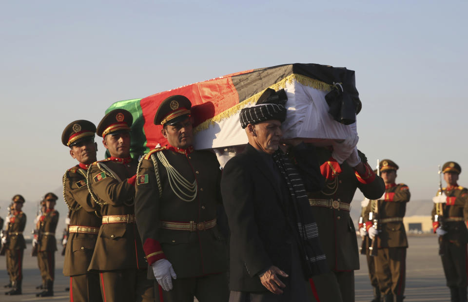 Afghan President Ashraf Ghani, foreground, and Afghan honor guards carry the coffin of Japanese physician Tetsu Nakamura during a ceremony before transporting his body to his homeland, at the Hamid Karzai International Airport in Kabul, Afghanistan, Saturday, Dec. 7, 2019. Nakamura was killed earlier this week in a roadside shooting in eastern Afghanistan. (AP Photo/Rahmat Gul)