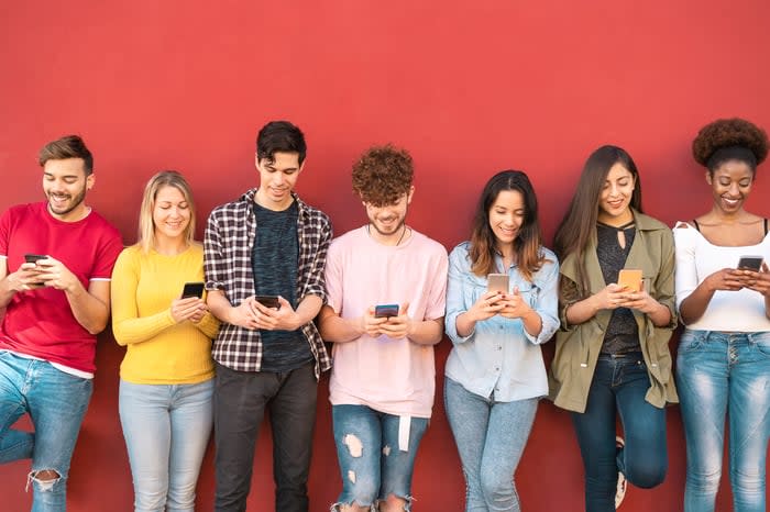 A group of young people use their smartphones outside.