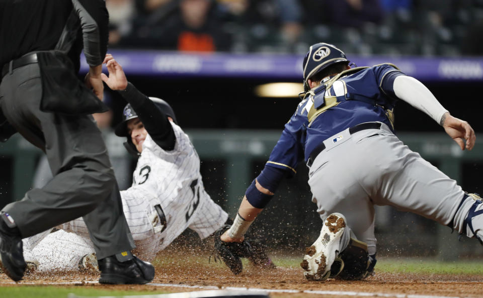 Milwaukee Brewers catcher Yasmani Grandal, right, applies a late tag as Colorado Rockies' Sam Hilliard scores on a single hit by Tony Wolters in the third inning of a baseball game Friday, Sept. 27, 2019, in Denver. (AP Photo/David Zalubowski)