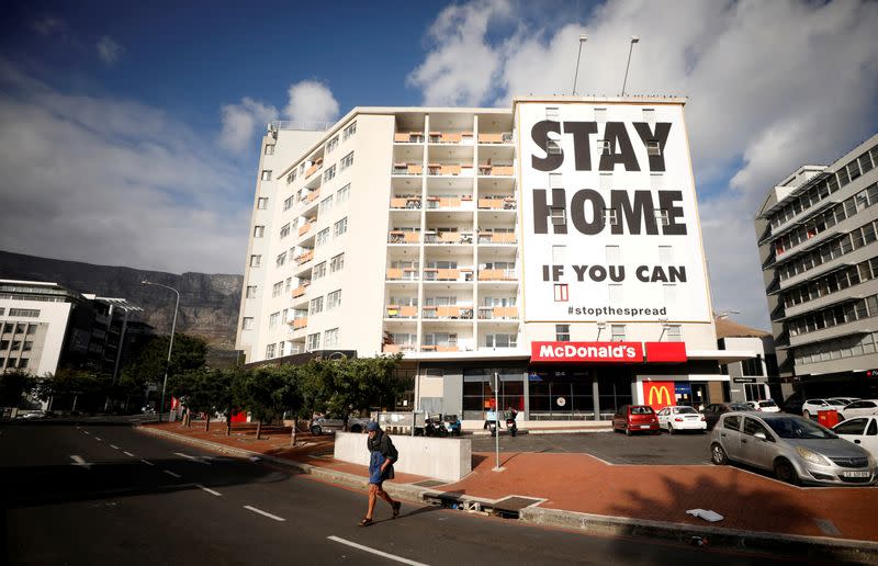 FILE PHOTO: A man walks past a poster covering the side of a building ahead of a 21 day lockdown aimed at limiting the spread of coronavirus disease (COVID-19), in Cape Town