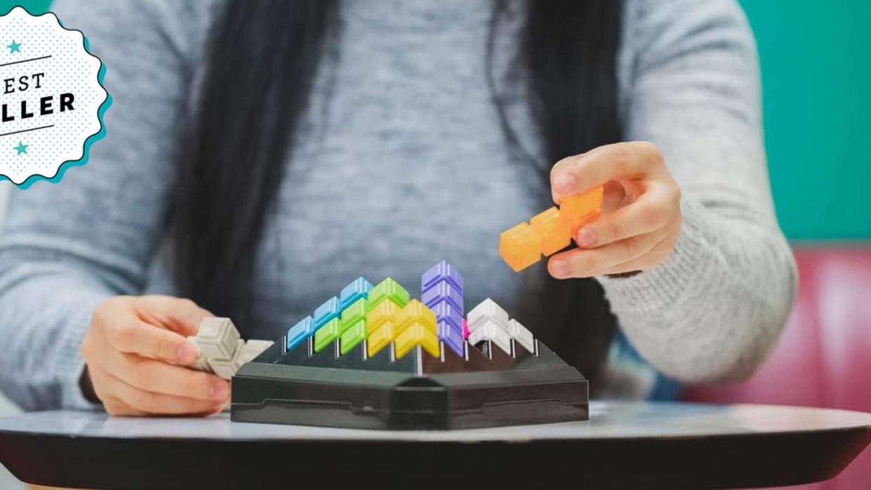 woman trying to solve kanoodle puzzle