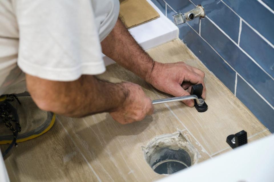 A person in a white shirt conducts a toilet flange swap.