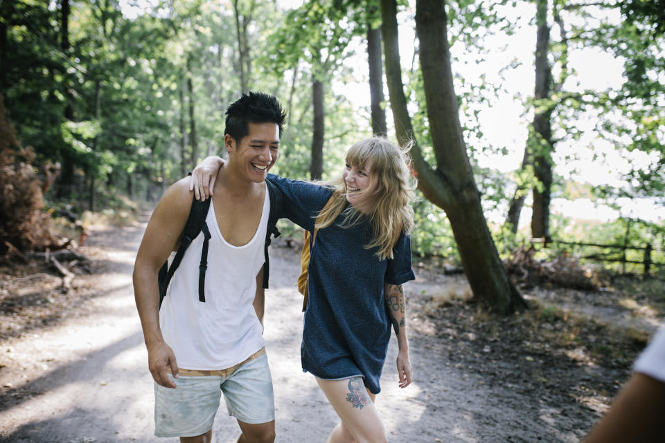 A couple walking together and chatting in the afternoon sun while making their way to a lake with some friends.