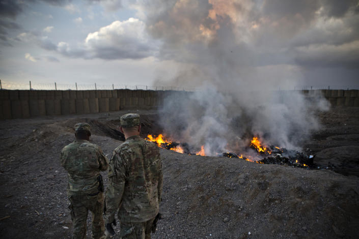 U.S. Army soldiers watch garbage burn at a base in Afghanistan.