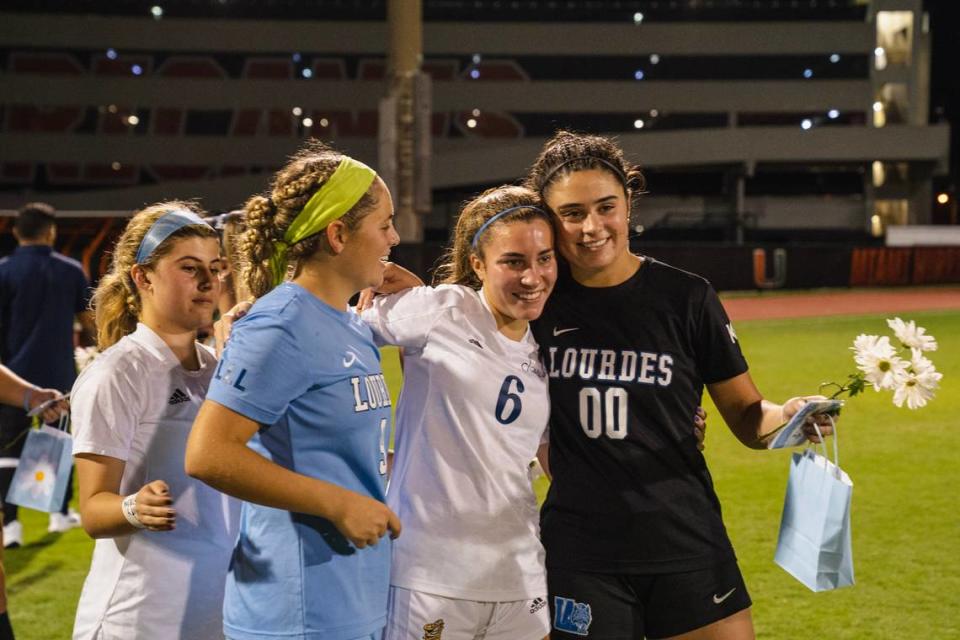 Las jugadoras de Lourdes Rebecca Sampedro (izquierda) y Gabriella Paredes (derecha) posan para una foto con Nina Puig de Carrollton (camiseta blanca) en un reciente partido entre las dos escuelas dedicado a la prima de Puig, Katy, quien permanece hospitalizada tras resultar herida en un accidente náutico en los Cayos de la Florida el fin de semana del Día del Trabajo, el cual también cobró la vida de la estudiante de Lourdes Lucy Fernández y en el que múltiples jugadoras de ambas escuelas sufrieron lesiones.