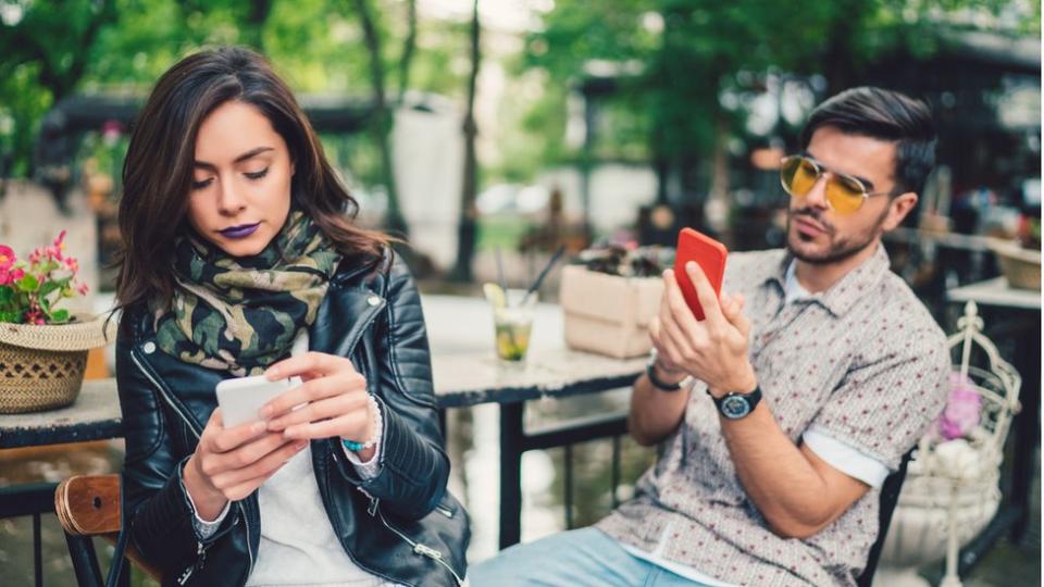 Pareja cada uno mirando su móvil