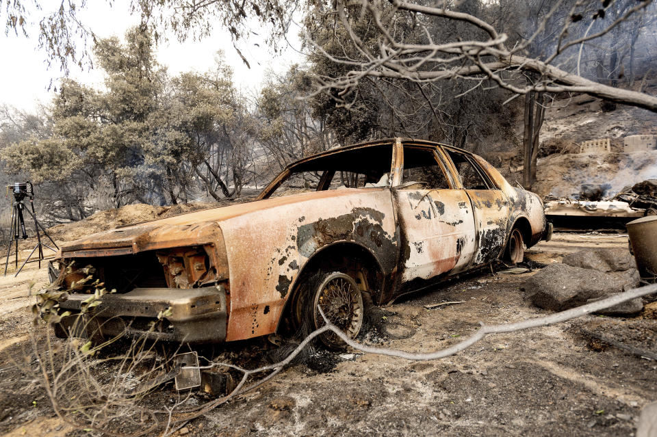 A burned vehicle rests along Pine Canyon Rd. as the Lake Fire burns in the Angeles National Forest, Calif., north of Santa Clarita on Thursday, Aug. 13, 2020. An enormous plume of smoke was visible across much of Southern California after the fire broke out Wednesday afternoon in dense forest land. (AP Photo/Noah Berger)