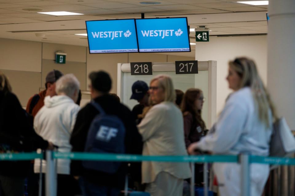Travellers wait in a queue at a Westjet counter in Toronto Pearson International airport on Sunday after hundreds of flights were cancelled due to strike action (Getty Images)