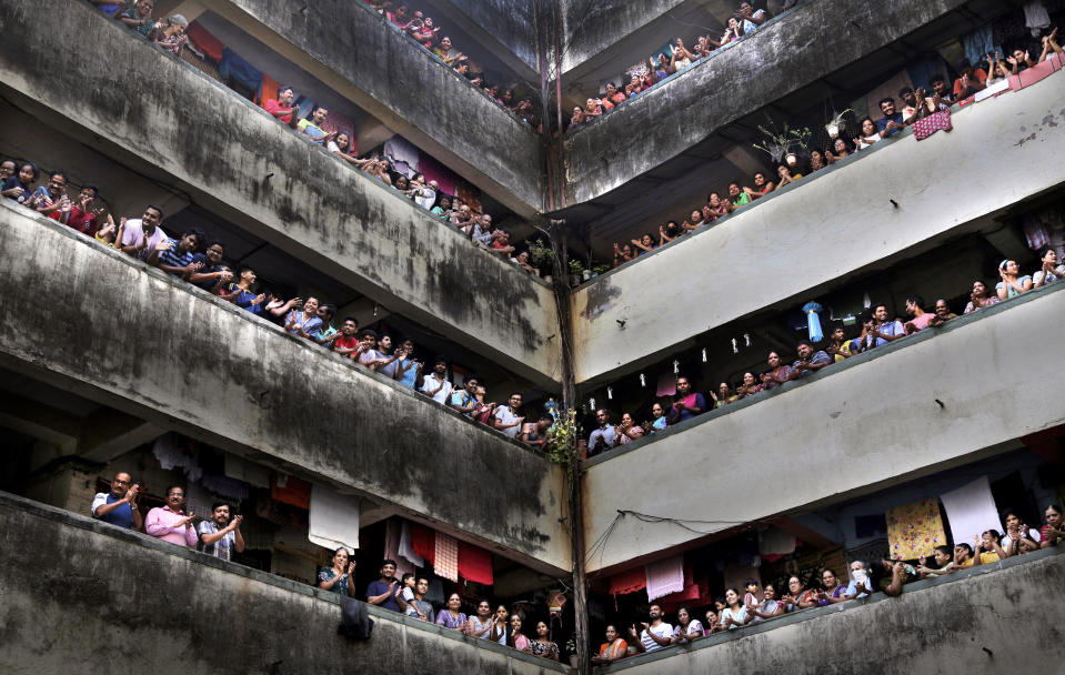 FILE - In this Sunday, March 22, 2020, file photo, people clap from balconies in a show of appreciation to health care workers during a 14-hour "people's curfew" called by Prime Minister Narendra Modi in order to stem the rising coronavirus caseload, at a Chawl in Mumbai, India. As India and other South Asian nations brace for the likely spread of the virus, they are facing another battle: reams of misinformation, misleading rumors and false claims. The WhatsApp messaging app was flooded with claims that “cosmic level sound waves” generated by a collective cheer Modi had asked the country of 1.3 billion to participate in last Sunday had weakened the virus in India. (AP Photo/Rafiq Maqbool)