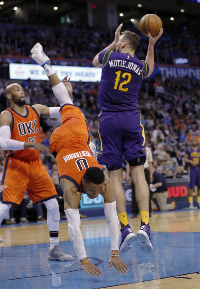 Oklahoma City Thunder guard Russell Westbrook (0) falls after fouling New Orleans Pelicans forward Donatas Motiejunas (12) during the first half of an NBA basketball game in Oklahoma City, Sunday, Feb. 26, 2017. (AP Photo/Alonzo Adams)