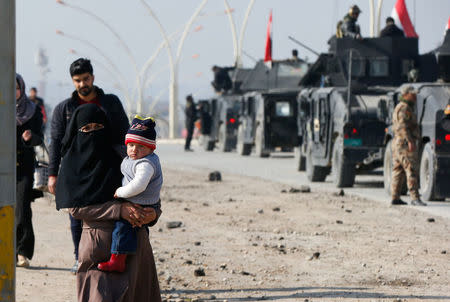 A woman carries her daughter as the civilians leave the city to escape from clashes during a battle with Islamic State militants, in al-Zirai district in Mosul, Iraq, January 19, 2017. REUTERS/Muhammad Hamed