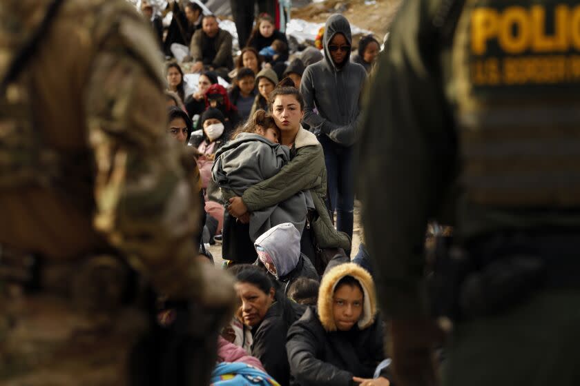 U.S. border, United States-May 11, 2023-U.S. border patrol agents make contact with migrants hoping to cross into the United States from Tijuana, Mexico on May 11, 2023. Some migrants have been waiting a week in an area south of the second border wall in anticipation of a change in immigration policy, Title 42, which may allow them to apply for asylum. U.S. border patrol agents give out one bottle of water and one granola bar to each person. There are approximately 500 people in this one camp. (Carolyn Cole / Los Angeles Times)