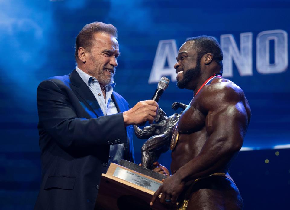 Arnold Schwarzenegger presents the first-place trophy to Brandon Curry for the Pro Bodybuilding award during the Arnold Classic Finals on March 5, 2022 at the Greater Columbus Convention Center.