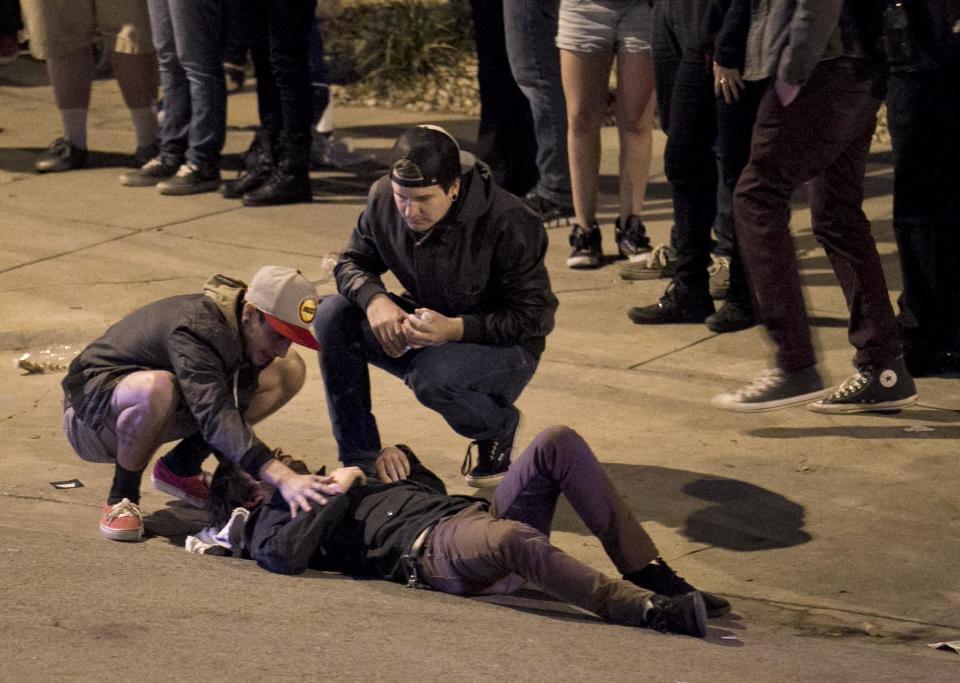 Bystanders tend to a man who was struck by a vehicle on Red River Street in downtown Austin, Texas, during SXSW on Wednesday March 12, 2014. Police say two people were confirmed dead at the scene after a car drove through temporary barricades set up for the South By Southwest festival and struck a crowd of pedestrians. (AP Photo/Austin American-Statesman, Jay Janner)