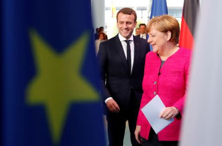 FILE PHOTO: German Chancellor Angela Merkel and French President Emmanuel Macron arrive to a news conference at the Chancellery in Berlin, Germany, May 15, 2017. REUTERS/Fabrizio Bensch/File Photo