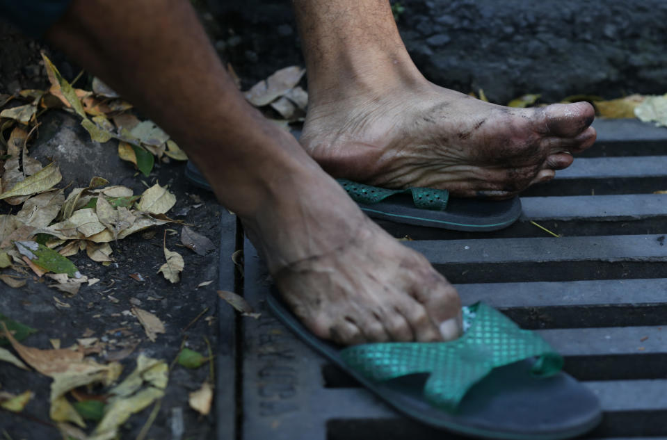 A man rests his feet after scores of Central American migrants, representing the thousands participating in a caravan trying to reach the U.S. border, undertook an hours-long march to the office of the United Nations' humans rights body in Mexico City, Thursday, Nov. 8, 2018. Members of the caravan which has stopped in Mexico City demanded buses Thursday to take them to the U.S. border, saying it is too cold and dangerous to continue walking and hitchhiking.(AP Photo/Rebecca Blackwell)