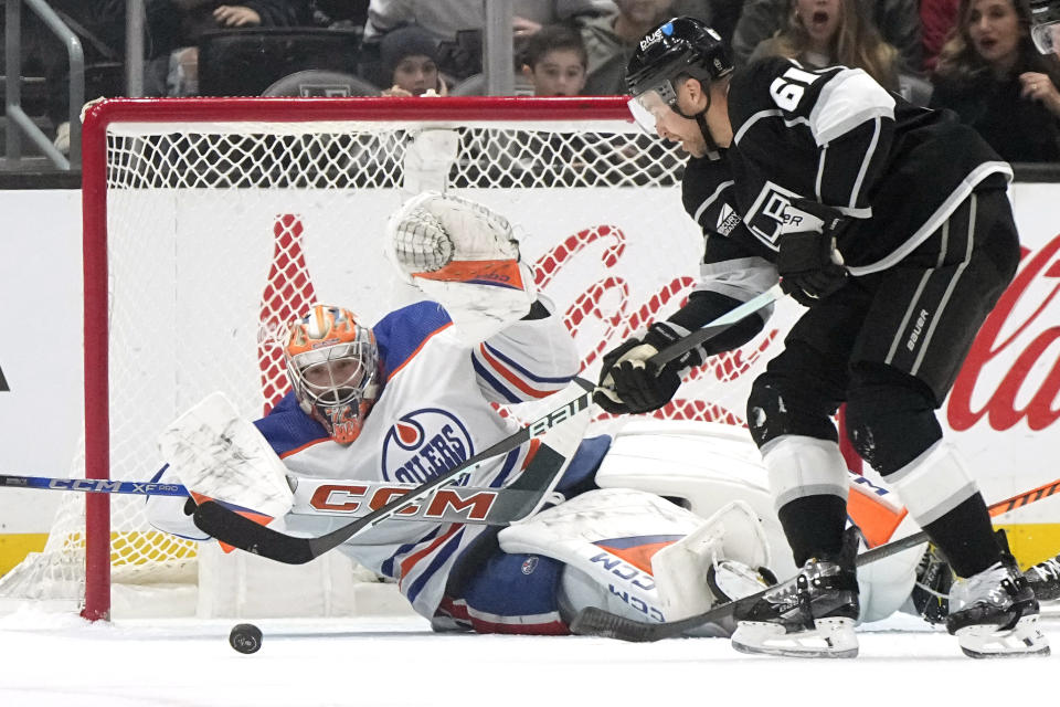 Edmonton Oilers goaltender Stuart Skinner, left, dives to stop a shot by Los Angeles Kings center Trevor Lewis during the first period of an NHL hockey game Saturday, Dec. 30, 2023, in Los Angeles. (AP Photo/Mark J. Terrill)