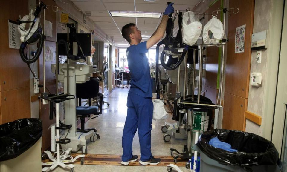 Nurse Alex Krajek hangs up his air-purifying respirator after working in a patient room in a wing housing coronavirus patients at UW Health University Hospital in Madison, Wisconsin Wednesday.