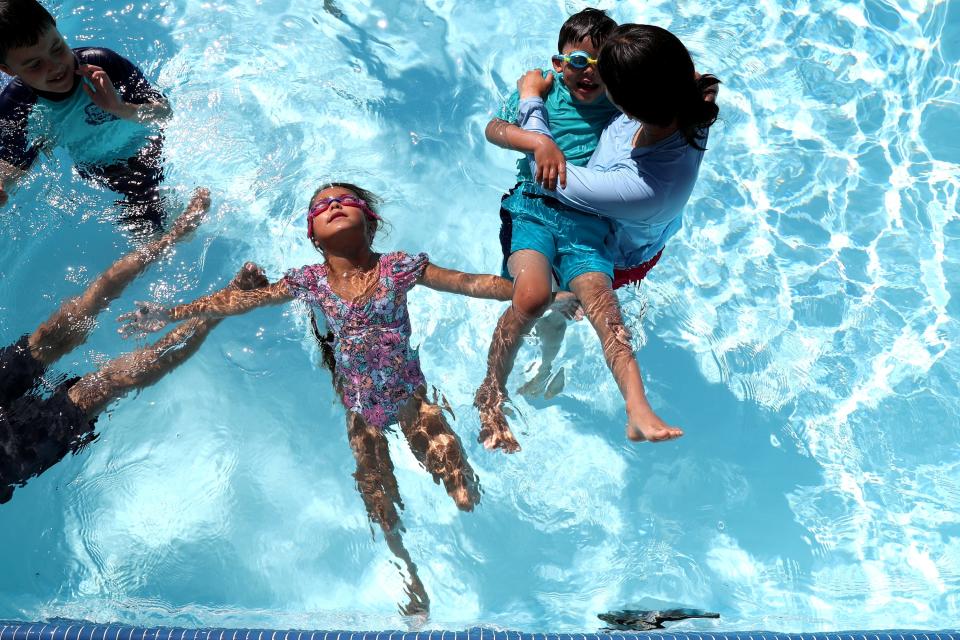 Callie Geronimo, 7, center, floats as Desert Recreation District swim instructor Brianna Valadez assists August Gallegos, 6, during swim lessons at the Cathedral City High School pool in Cathedral City, Calif., on Wed., July 26, 2023.