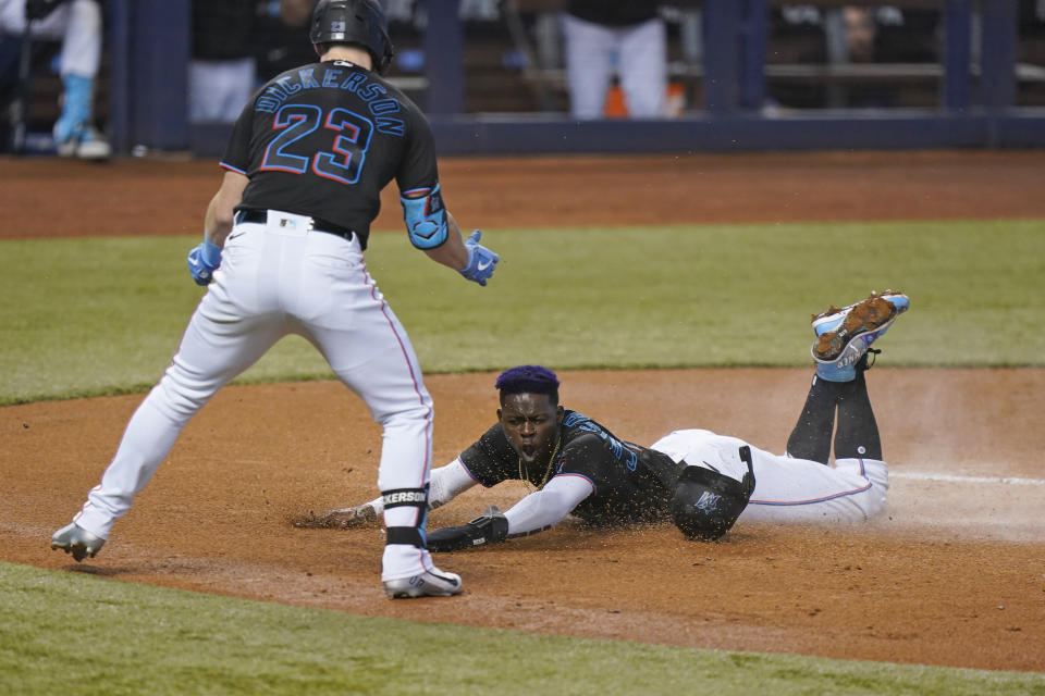 Miami Marlins' Corey Dickerson (23) celebrates as Jazz Chisholm Jr. slides into home to score on a sacrifice fly ball hit by Jesus Aguilar during the first inning of a baseball game against the Atlanta Braves, Saturday, June 12, 2021, in Miami. (AP Photo/Wilfredo Lee)