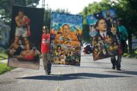 Jun 10, 2016; Louisville, KY, USA; Terry Wilson (left), and Dwight Stokes , both of Indianapolis , carry murals in front of the boyhood home of Muhammad Ali on Grand Avenue before the the passing of the funeral processional. Mandatory Credit: Joshua Lindsey-USA TODAY Sports