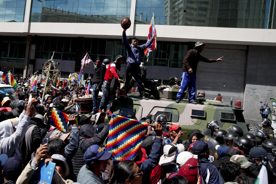 Anti-government demonstrators stand atop a military vehicle during a funeral procession for people killed in clashes between supporters of former President Evo Morales and security forces, in La Paz, Bolivia, Thursday, Nov. 21, 2019. At least eight people were killed Tuesday when security forces cleared a blockade of a fuel plant by Morales' backers in the city of El Alto. (AP Photo/Natacha Pisarenko)