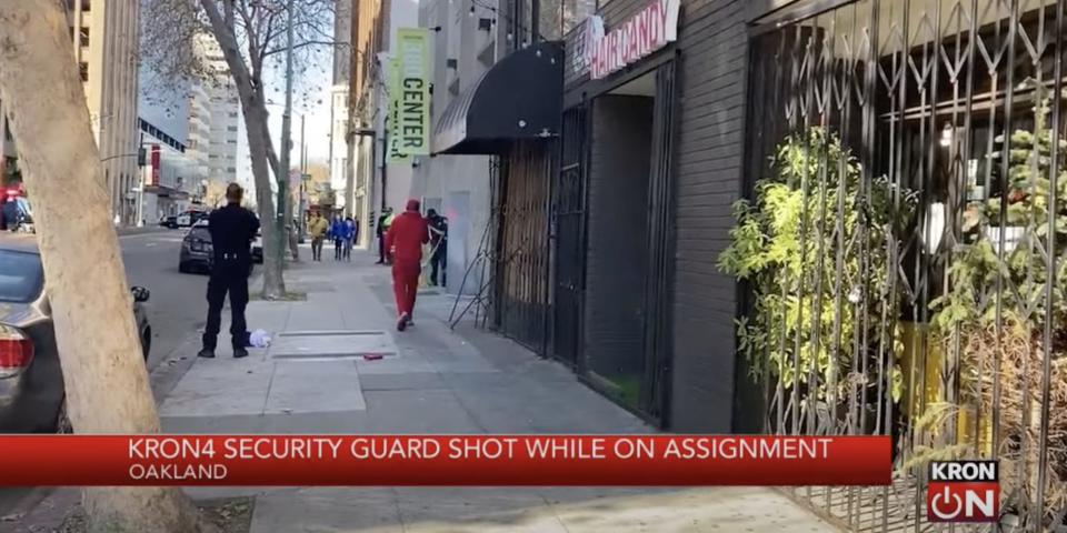 A still from local news footage taken after the crew's security guard was shot. It is a view of a street in Oakland, with the chyron "KRON4 security guard shot while on assignment."