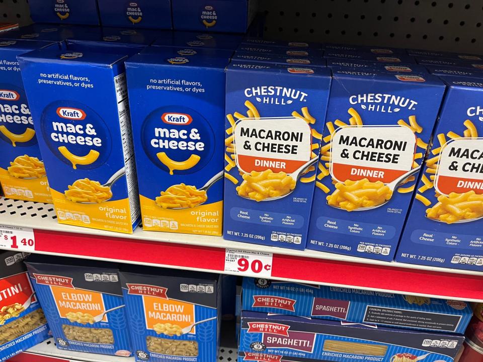 Blaue Schachteln von Chestnut Hill Macaroni & Cheese Dinner stehen neben Kraft Mac & Cheese in einem Regal bei Family Dollar.