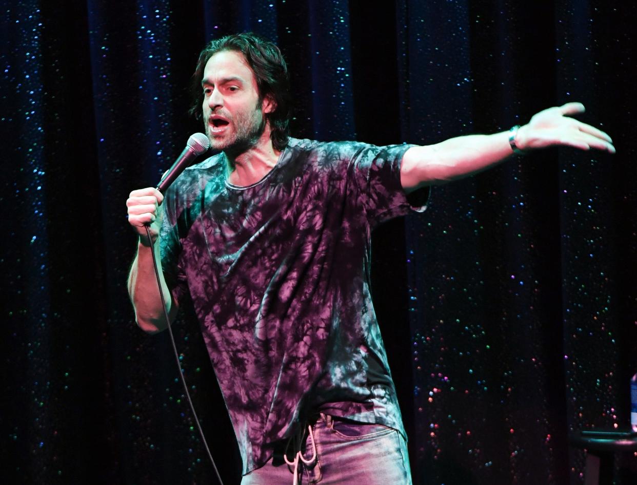 Chris D'Elia talking into microphone and holding arm out emphatically