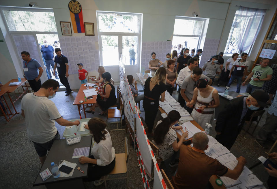 People at a polling station during a parliamentary election in Yerevan, Armenia, Sunday, June 20, 2021. Armenians are voting in a national election after months of tensions over last year's defeat in fighting against Azerbaijan over the separatist region of Nagorno-Karabakh. (AP Photo/Sergei Grits)