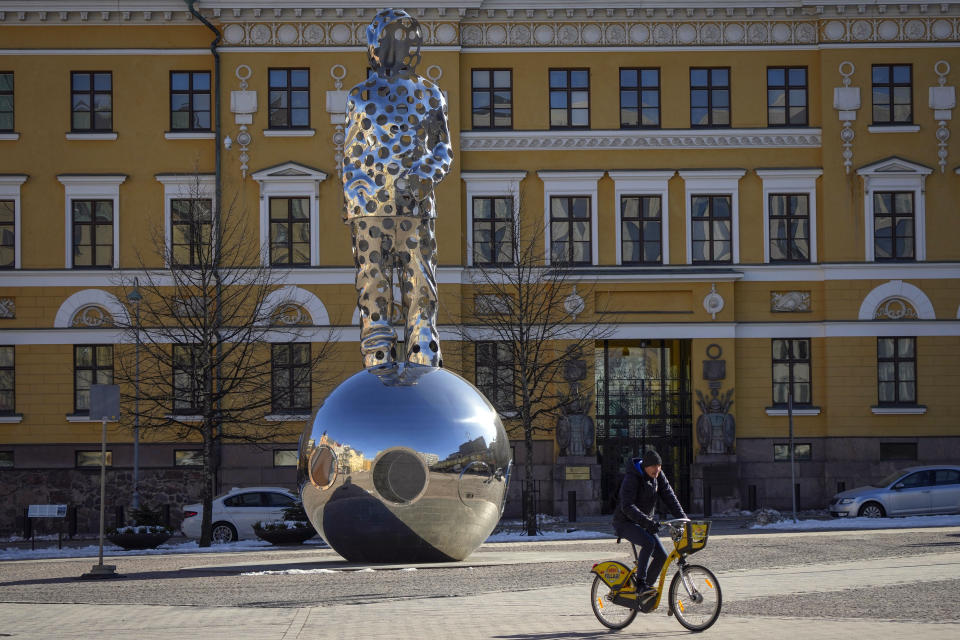 A man bicycles past a National memorial of the Winter War 1939-1940 in front of building of Ministry of Defence in Helsinki, Finland, Monday, April 3, 2023. NATO Secretary-General Jens Stoltenberg said Finland will officially join the military alliance on Tuesday. The green light comes days after Turkey's parliament endorsed Finland's accession. (AP Photo/Sergei Grits)