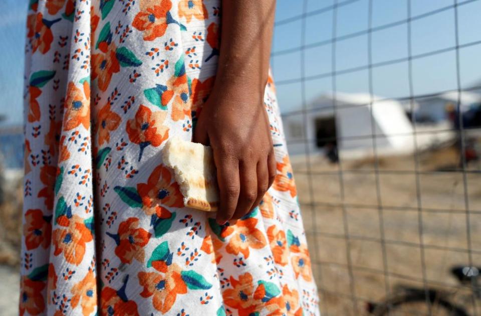 A child clutches some bread outside a camp for migrants and refugees on the Greek island of Lesbos.