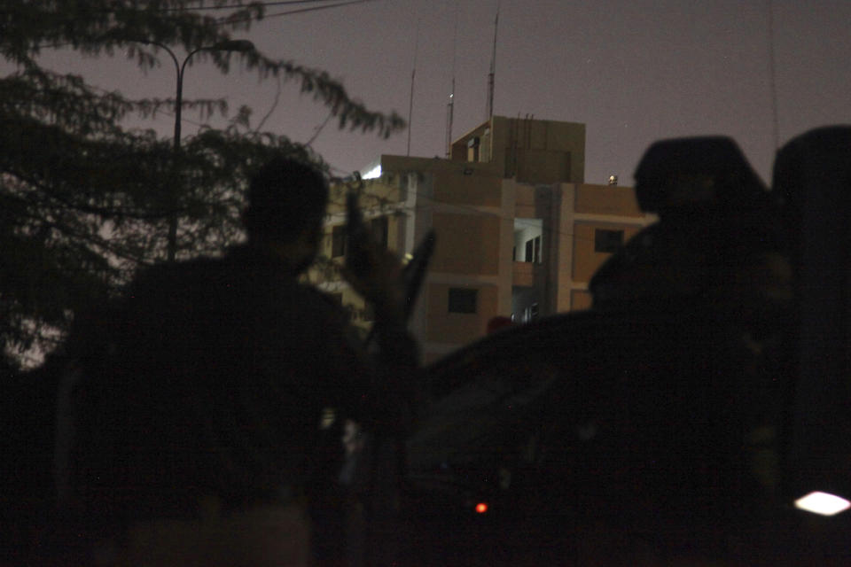 A police officer takes position beside his vehicle close to the incident site following gunmen attack on police headquarters, in Karachi, Pakistan, Friday, Feb. 17, 2023. Gunfire erupted outside of police headquarters in Pakistan's largest city on Friday, as security forces rushed to stave off what appeared to be a bold attack in the heart of Karachi, police and officials said. (AP Photo/Ikram Suri)