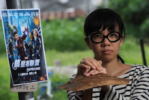 Political activist Ger Choi Tze-kwan stands next to a poster of the movie The Avengers, that has been changed to include images of Hong Kong politicians in Hong Kong on May 12