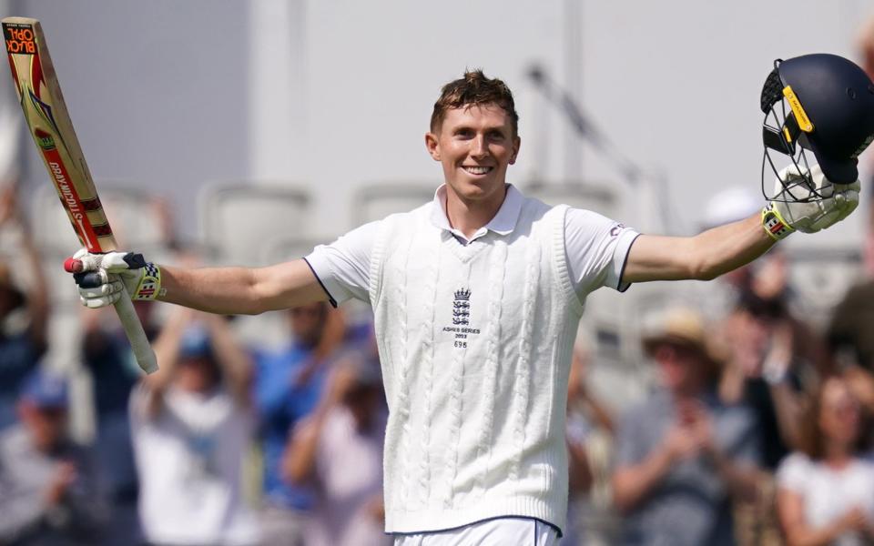 Zak Crawley raises his arms aloft, holding bat and helmet in each hand