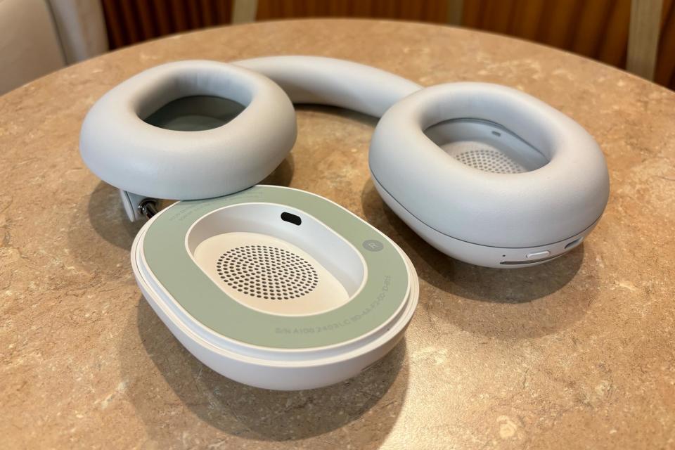 <p>White headphones laying flat on a small table, one ear pad removed.</p>
