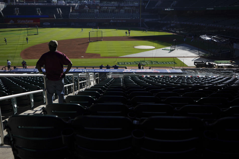 A spectator watches the Los Angeles Dodgers warm-up before Game 1 of baseball's National League Championship Series between the Atlanta Braves and the Los Angeles Dodgers Saturday, Oct. 16, 2021, in Atlanta. (AP Photo/Brynn Anderson)