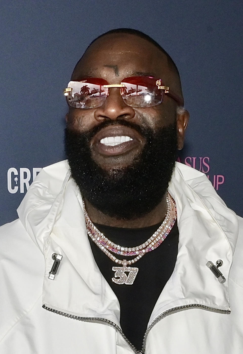 Rick Ross wore a white jacket, red sunglasses, and a large "37" pendant