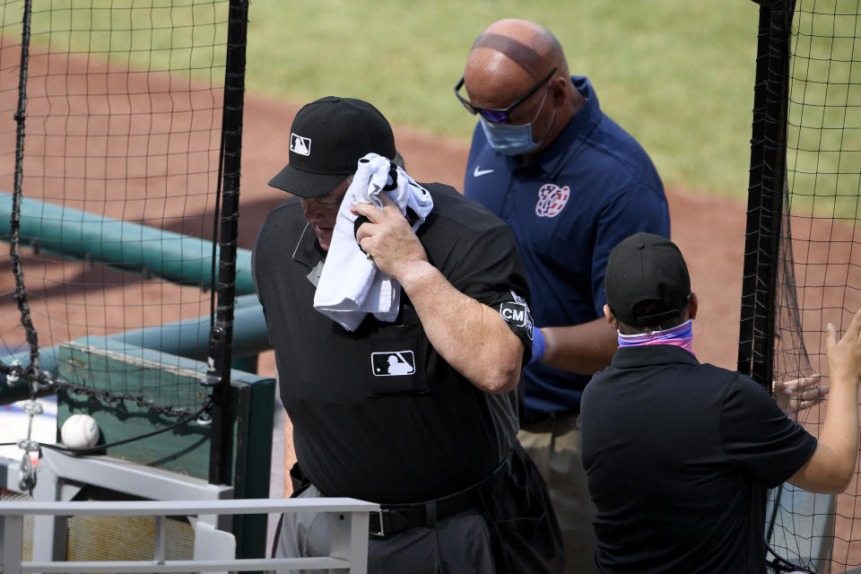 Home plate umpire Joe West, left, leaves the field after he was injured during the first inning of a baseball game between the Toronto Blue Jays and the Washington Nationals, Thursday, July 30, 2020, in Washington. (AP Photo/Nick Wass)